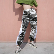 Women wearing camouflage jogger pants with elastic waist and side buttons, styled for a casual streetwear look.